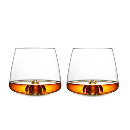 Two Normann Copenhagen Whisky Glasses are displayed against a plain white background, each holding a small amount of amber liquid and showcasing elegant Scandinavian glassware design.