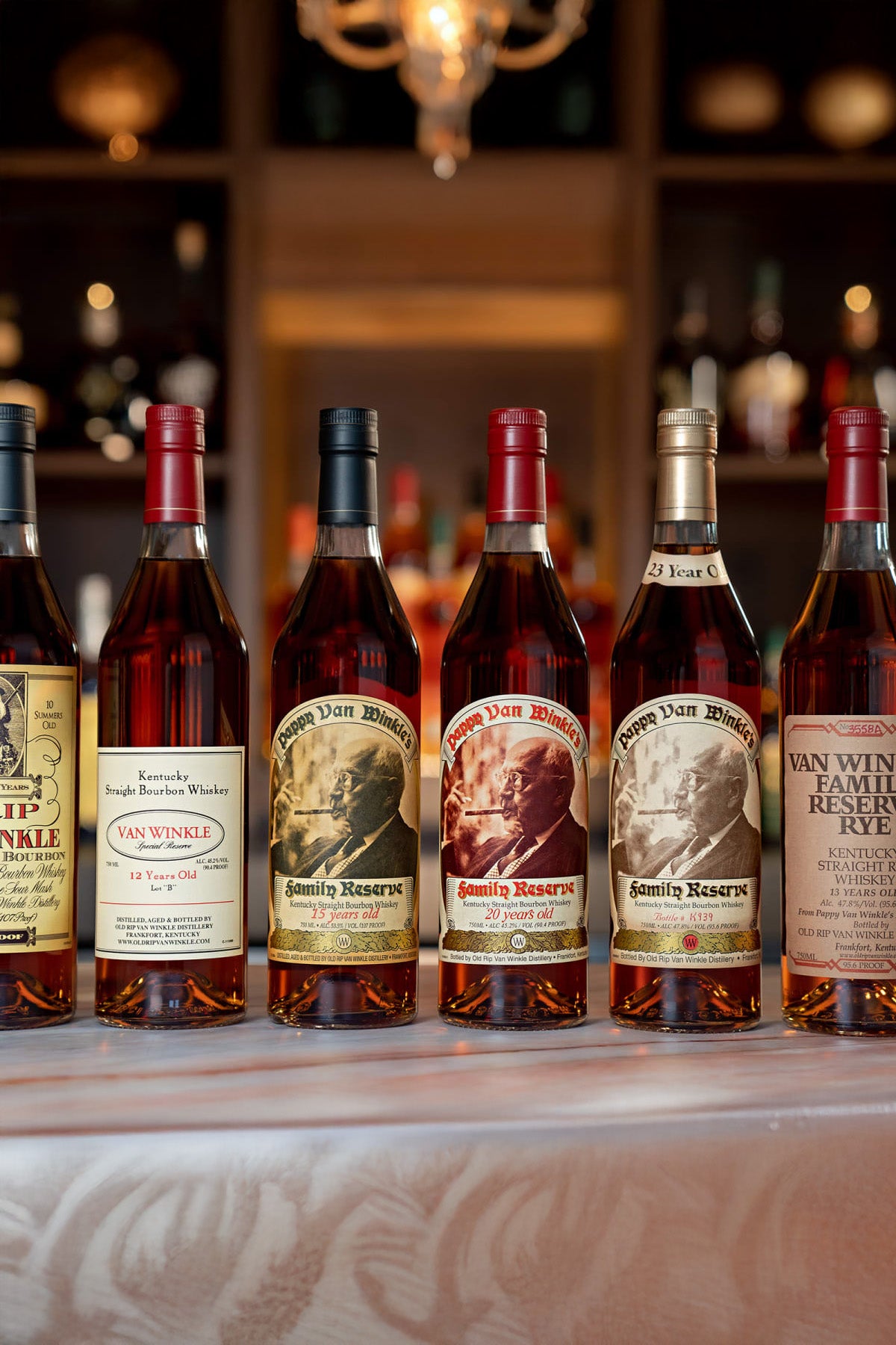 Row of Van Winkle bourbon bottles on a bar counter with blurred background