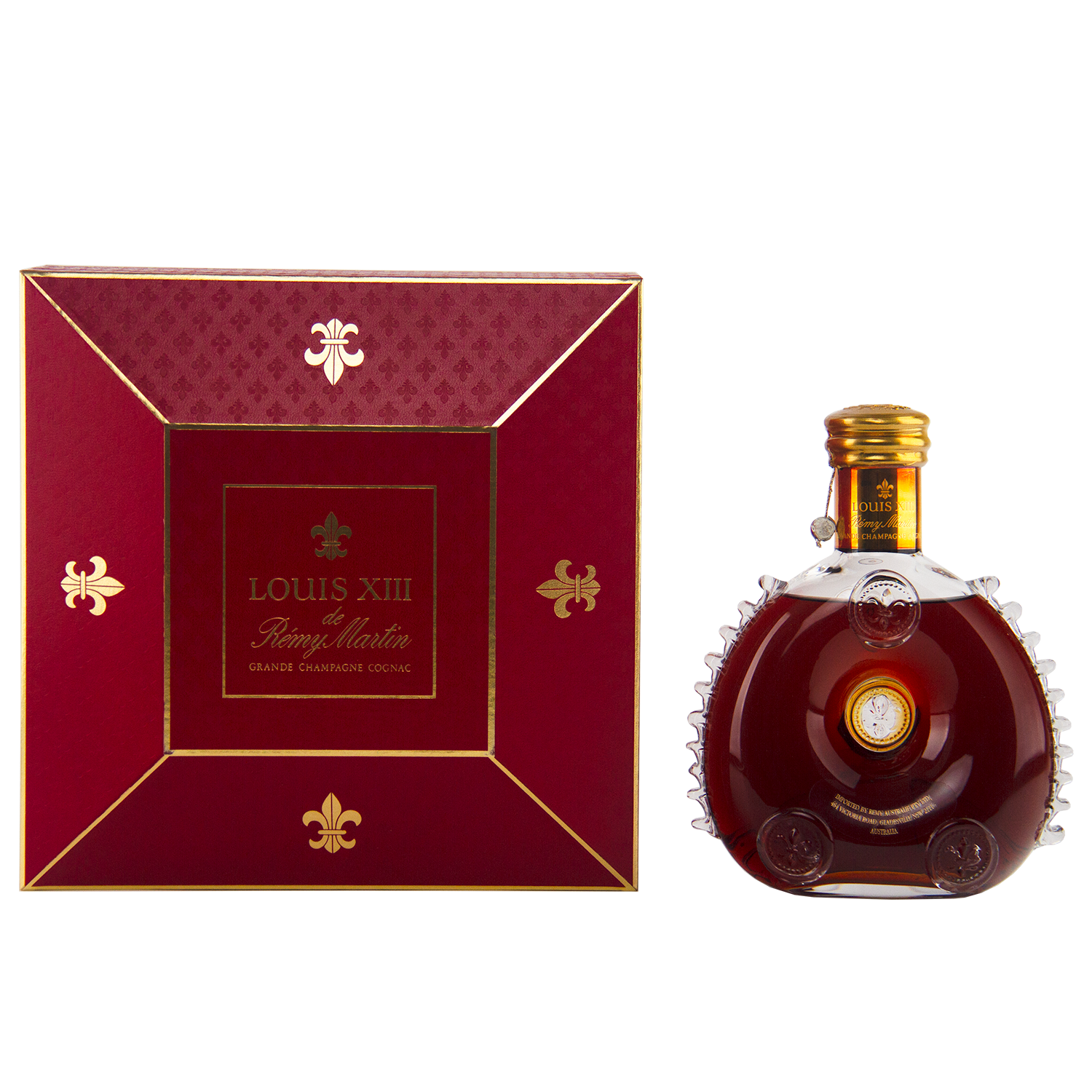 A 700mL bottle of Rémy Martin Louis XIII 1980s Edition Cognac Grande Champagne sits in a Baccarat crystal decanter beside its elegant red and gold box, both featuring the iconic branding.