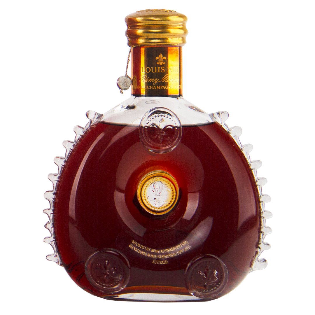 A 700mL bottle of Rémy Martin Louis XIII 1980s Edition Cognac Grande Champagne, with amber liquid in a round Baccarat crystal decanter adorned with gold accents and embossed decorative details.