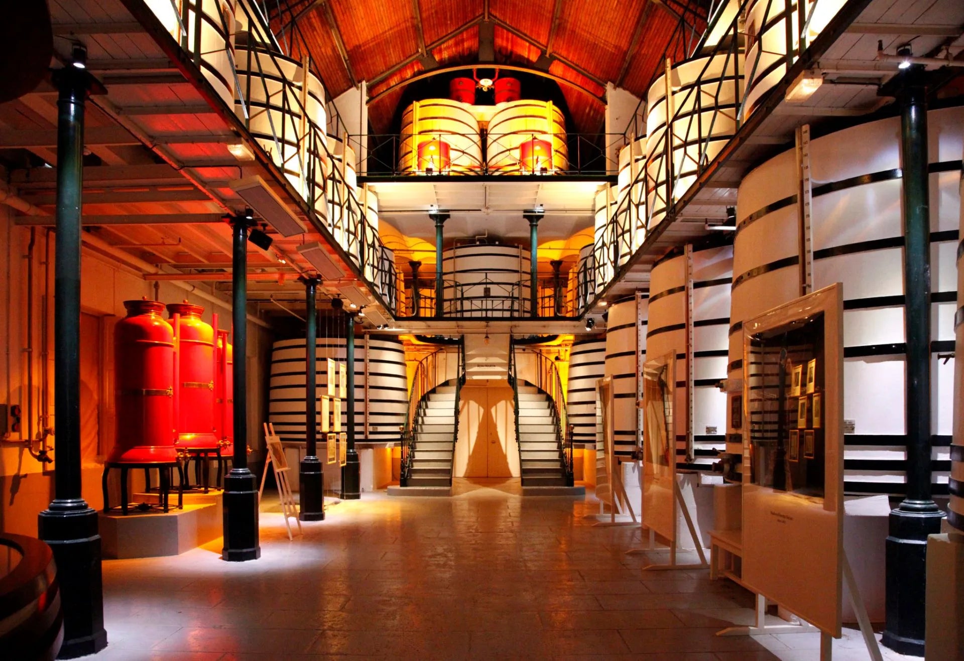 Large warehouse with rows of cylindrical tanks and a central staircase.