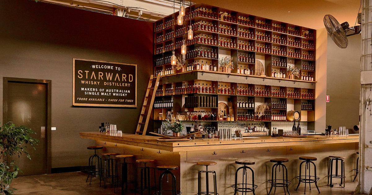 Bar area with shelves of bottles and a sign welcoming visitors to Starward Whisky Distillery.