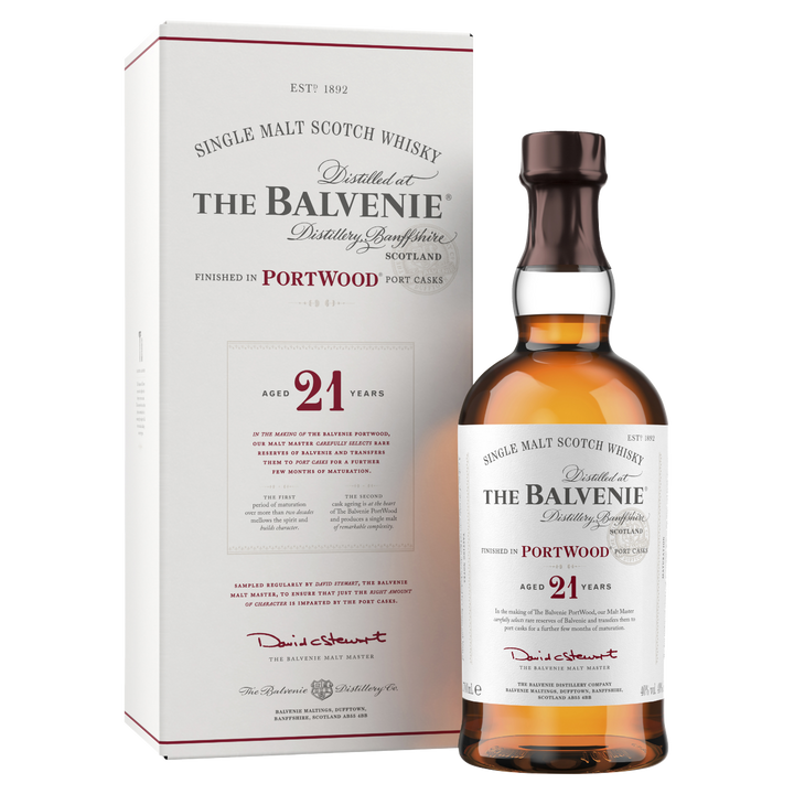 A bottle of The Balvenie PortWood 21 Year Old Single Malt Scotch Whisky stands before its matching white and red box, both displaying detailed branding that emphasizes its distinctive port cask finish.