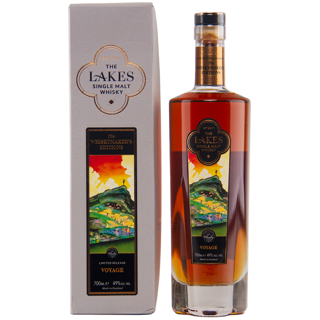 A 700ml bottle of The Lakes Whiskymaker’s Editions: Voyage Single Malt Whisky (49% ABV) stands beside its colorful scenic box. This limited release from The Lakes Distillery features hills and water on its label.