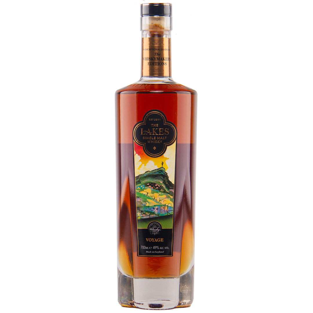 A tall bottle of The Lakes Whiskymaker’s Editions: Voyage Single Malt Whisky, with a colorful front label, holds dark amber spirit from The Lakes Distillery and is sealed with a cork top.