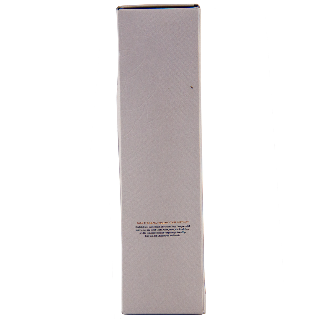 A tall, rectangular white box stands upright against a plain background, featuring a small block of text and faint circular patterns—an elegant presentation for The Lakes Whiskymaker’s Editions: Voyage Single Malt Whisky.