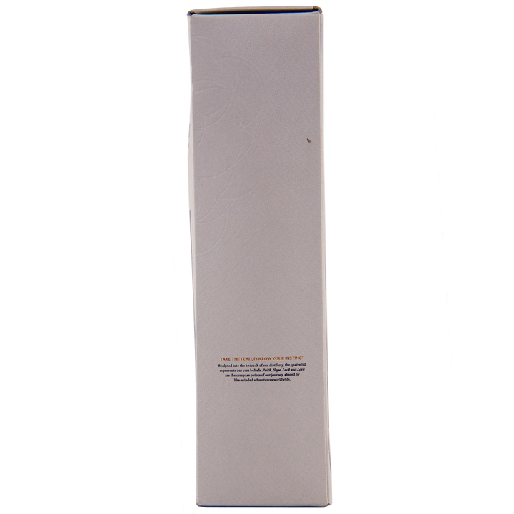 A tall, rectangular white box stands upright against a plain background, featuring a small block of text and faint circular patterns—an elegant presentation for The Lakes Whiskymaker’s Editions: Voyage Single Malt Whisky.