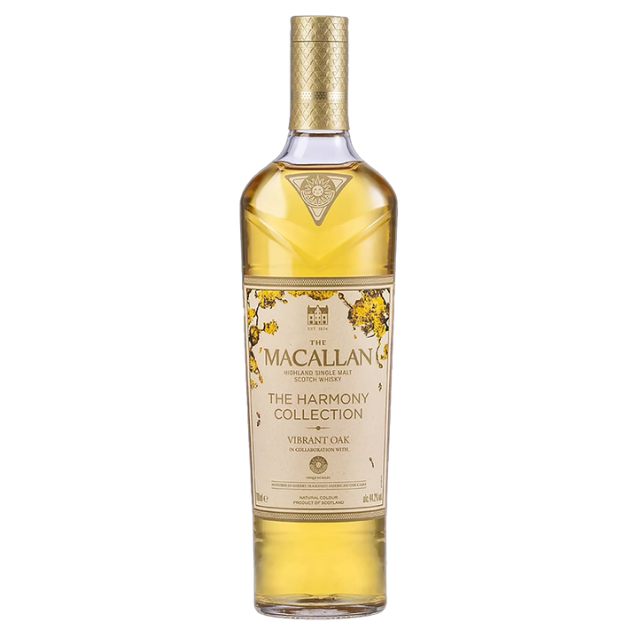 A limited edition bottle of The Macallan Harmony Collection Vibrant Oak Single Malt Scotch Whisky, featuring a gold and cream label, gold accents, and a patterned gold cap.