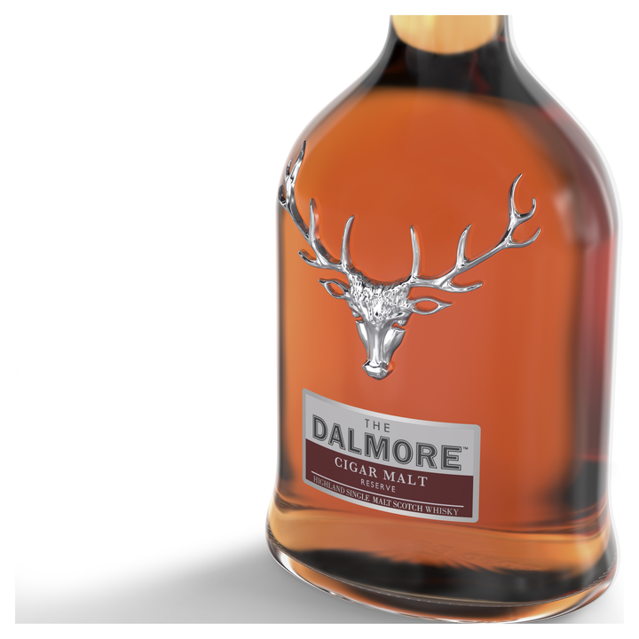 A close-up of The Dalmore Cigar Malt Reserve Single Malt Scotch Whisky bottle, showcasing its silver stag head emblem and amber liquid against a white background—ideal for pairing with a fine cigar.
