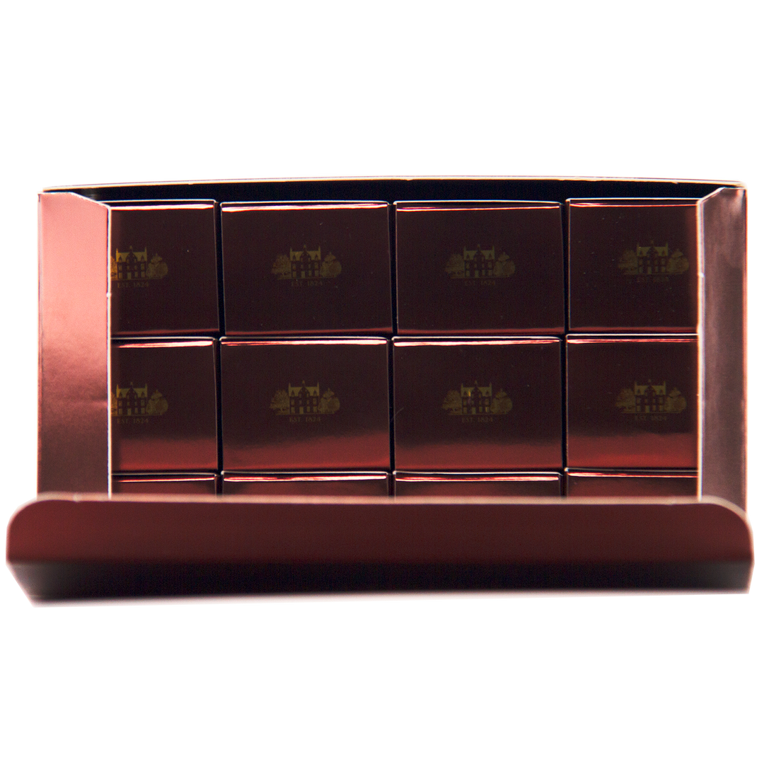 A box of twelve glossy, rectangular chocolates in a metallic tray—each embossed with gold logos—elegantly inspired by The Macallan 12 Year Old Sherry Oak Cask 12X50ml, with the lid partially open to reveal the luxurious treats inside.