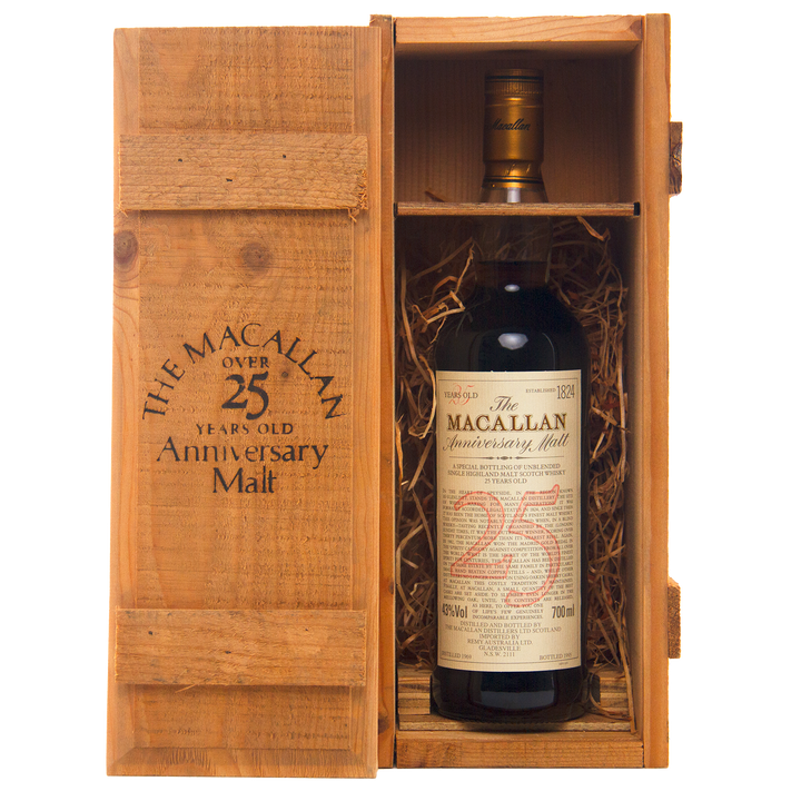 A bottle of The Macallan 1969 25 Year Old Anniversary Edition rests in a wooden presentation box with straw lining. The open lid reveals the whisky and branded text, emphasizing its prized sherry cask heritage.