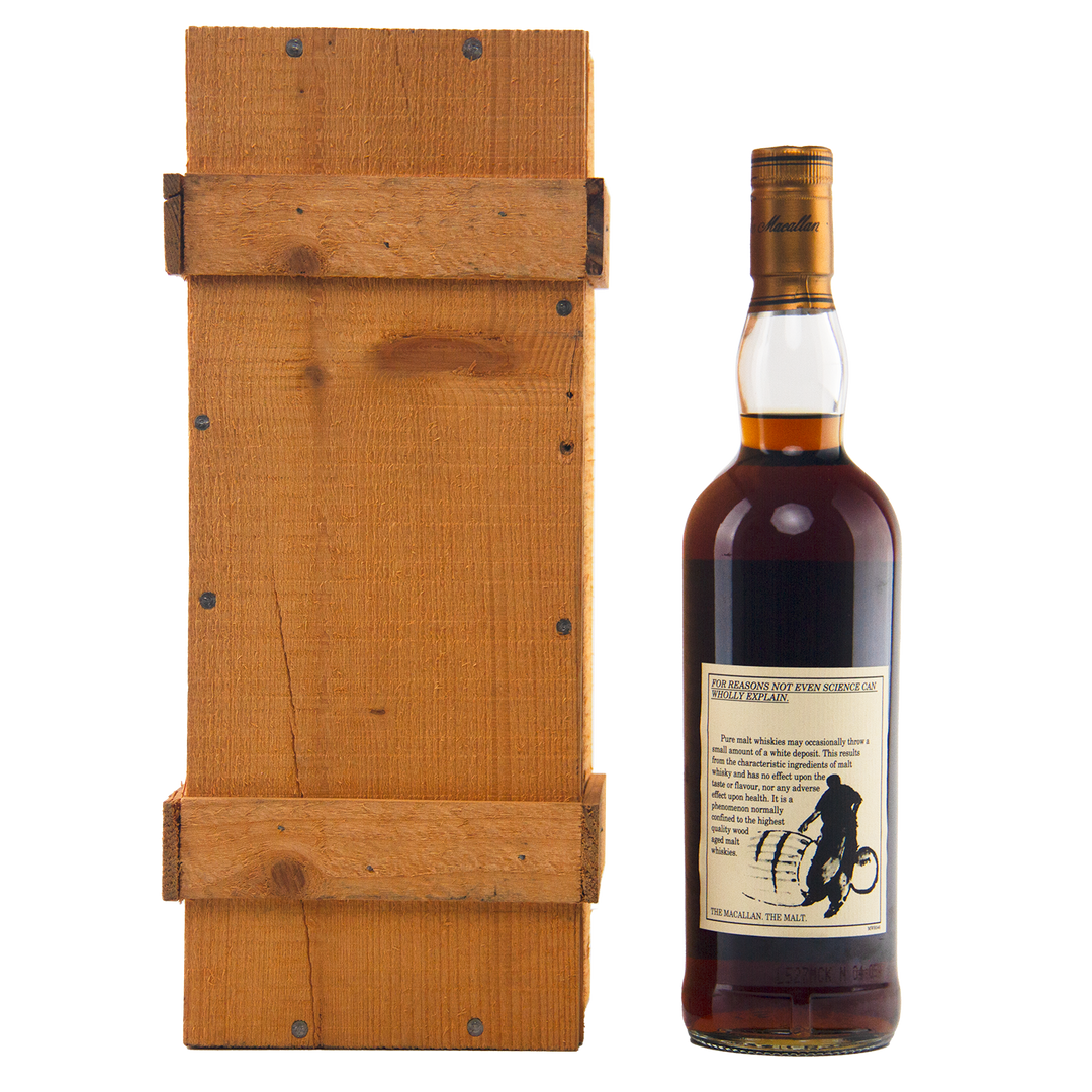 A bottle of The Macallan 1969 25 Year Old Anniversary Edition whisky, featuring a beige cyclist label, stands beside a rectangular wooden box with visible grain and slats, both displayed against a white background.