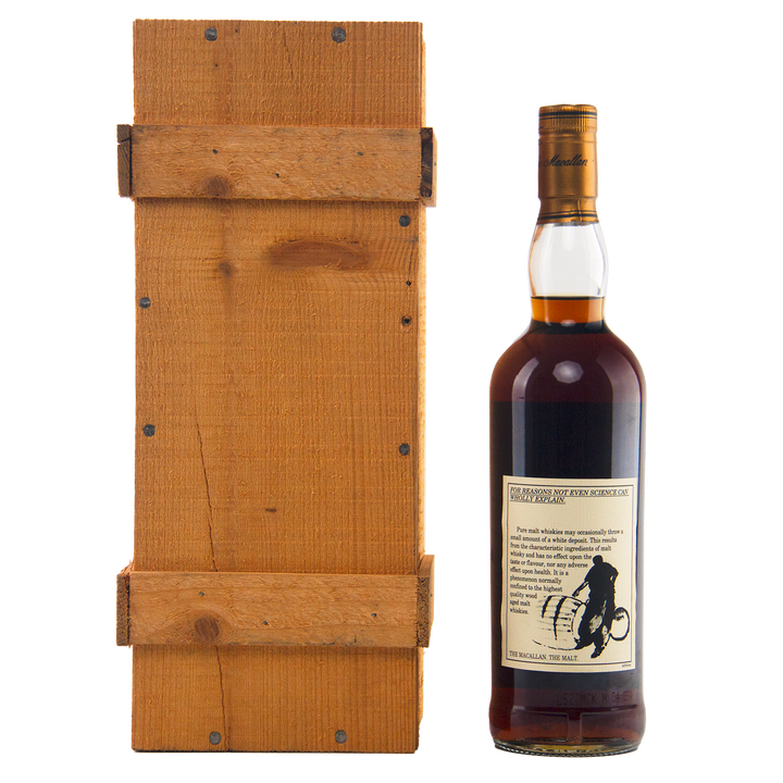 A bottle of The Macallan 1969 25 Year Old Anniversary Edition whisky, featuring a beige cyclist label, stands beside a rectangular wooden box with visible grain and slats, both displayed against a white background.