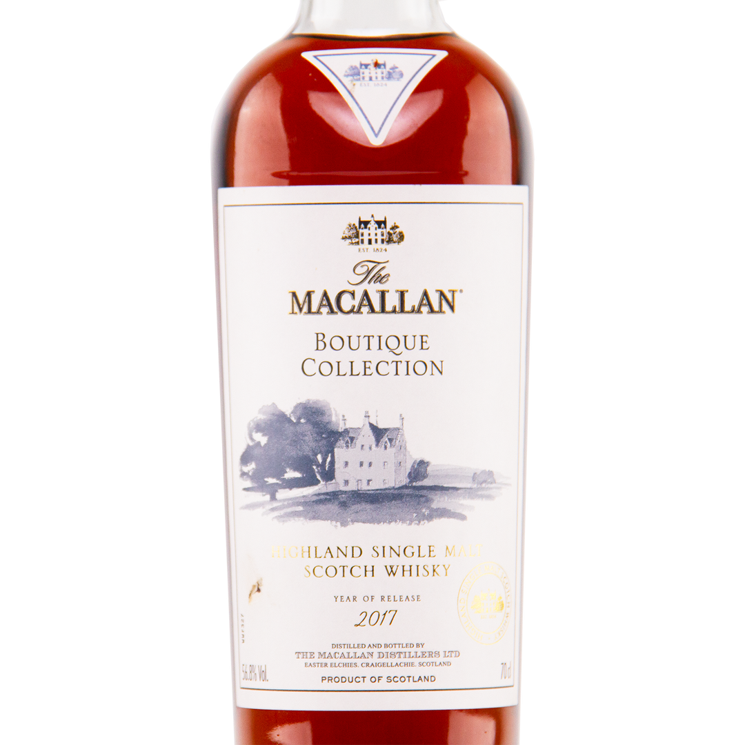 A bottle of The Macallan Boutique Collection 2017 Single Malt Whisky—travel retail exclusive with a white label showing a house illustration and gold and black text—one of the limited, highly sought-after Macallan releases.