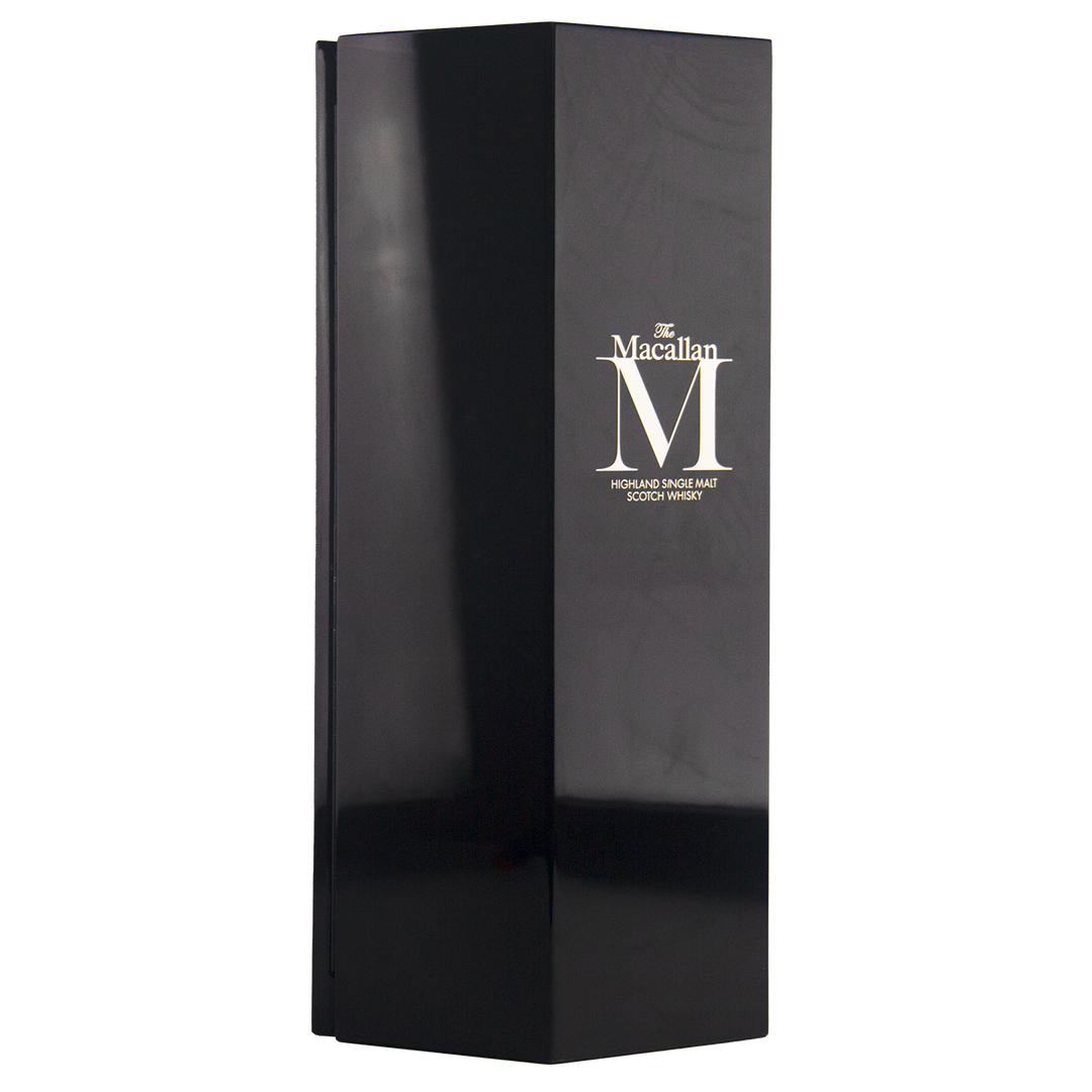 A tall, glossy black box with minimal design and gold text showcases The Macallan M (2017 First Release) Single Malt Scotch Whisky, reflecting sherry oak maturation and sharp-edged sophistication.