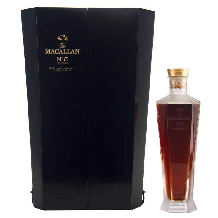 A bottle of The Macallan No 6 Single Malt Scotch Whisky, presented in a dark, elegant box with gold lettering and housed in a faceted decanter-style bottle topped with a gold cap.