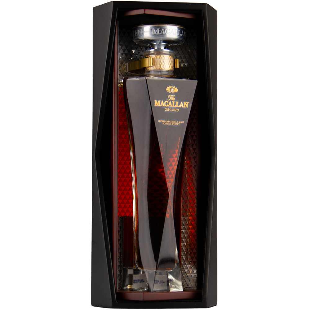 A bottle of The Macallan Oscuro Single Malt Scotch Whisky, matured in sherry-seasoned oak casks, is presented in a tall, uniquely shaped glass decanter with gold accents and an elegant black and red display box.