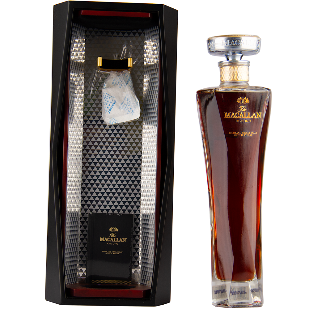 A tall bottle of The Macallan Oscuro Single Malt Scotch Whisky stands beside its geometric black and silver presentation box, open to display the bottle’s slot and a silica gel packet—matured in sherry-seasoned oak casks.
