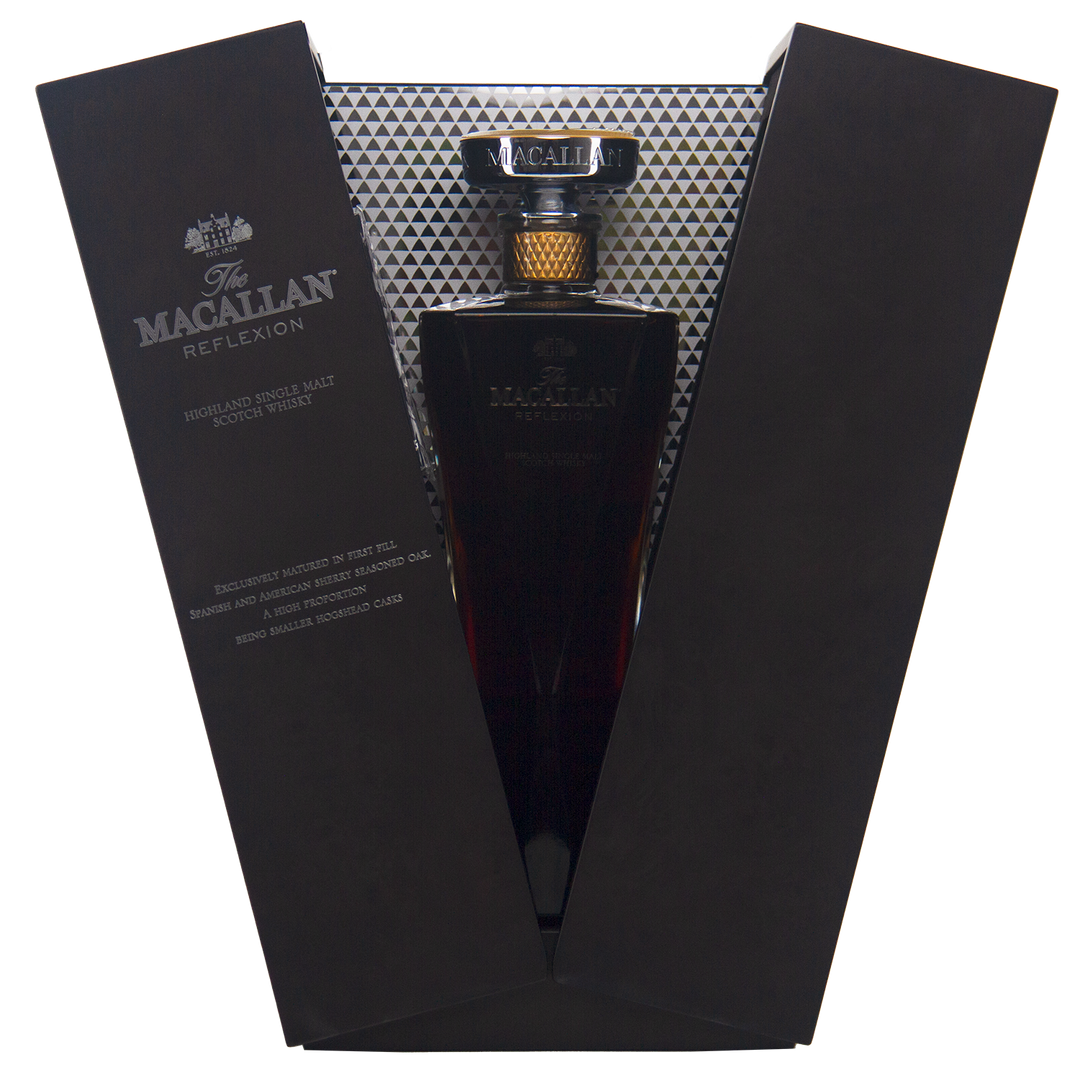 The Macallan Reflexion Single Malt Scotch Whisky is presented in a luxurious open black case with silver geometric lining, featuring a gold-capped bottle and elegant label that highlights its dark sherry cask-matured hue.
