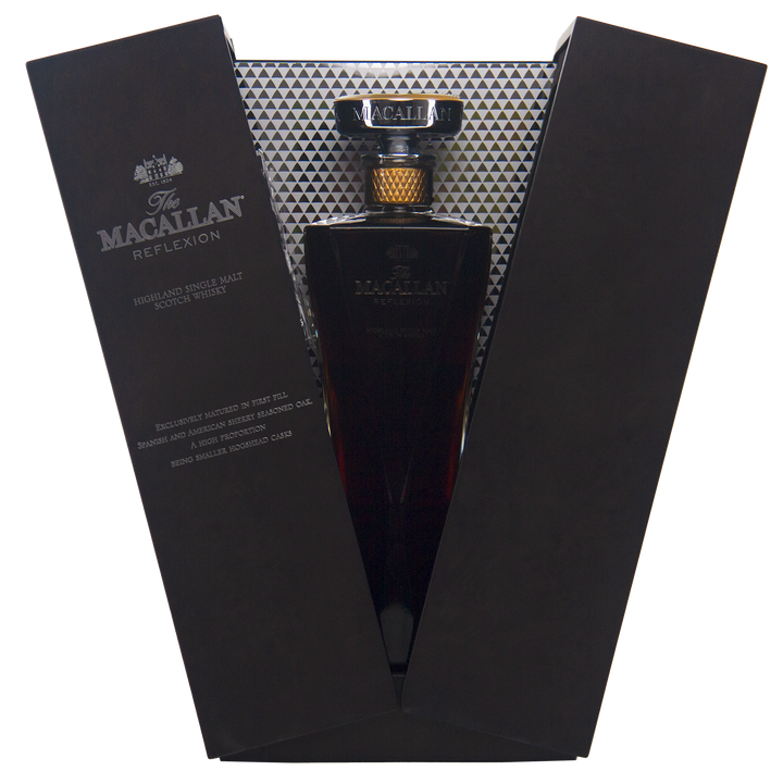 The Macallan Reflexion Single Malt Scotch Whisky is presented in a luxurious open black case with silver geometric lining, featuring a gold-capped bottle and elegant label that highlights its dark sherry cask-matured hue.