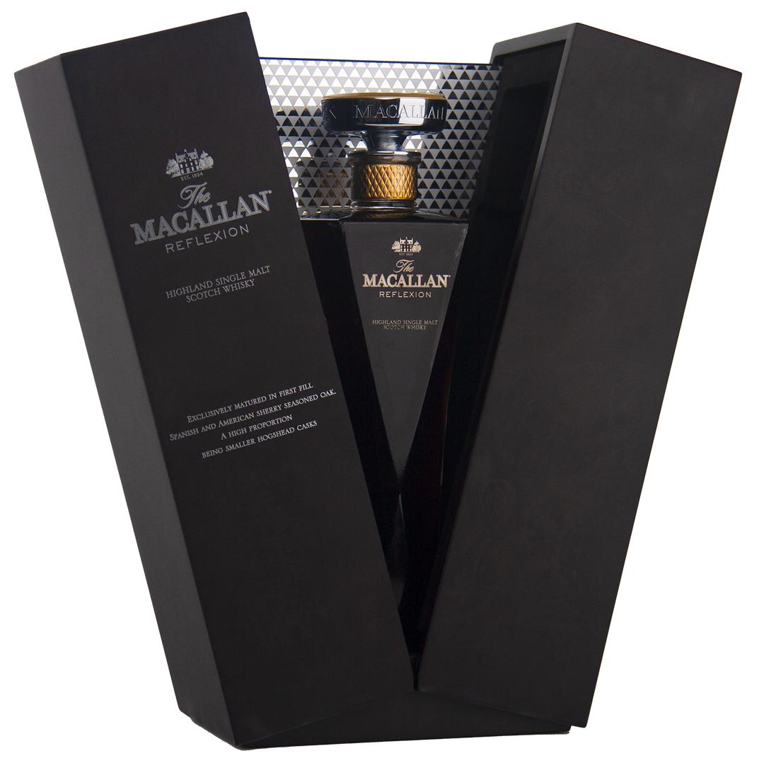 A bottle of The Macallan Reflexion Single Malt Scotch Whisky is shown in an open black presentation box with silver accents and gold lettering.