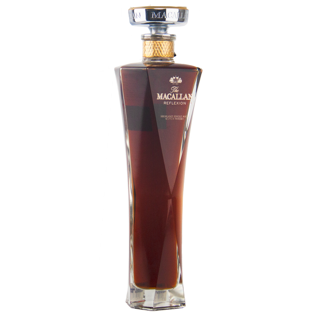 A tall, elegant bottle of The Macallan Reflexion Single Malt Scotch Whisky with a gold cap and rich amber liquid, featuring angled sides and a clear square base that highlight its sherry cask maturation, shown on a white background.