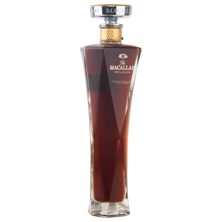 A tall, elegant bottle of The Macallan Reflexion Single Malt Scotch Whisky with a gold cap and rich amber liquid, featuring angled sides and a clear square base that highlight its sherry cask maturation, shown on a white background.