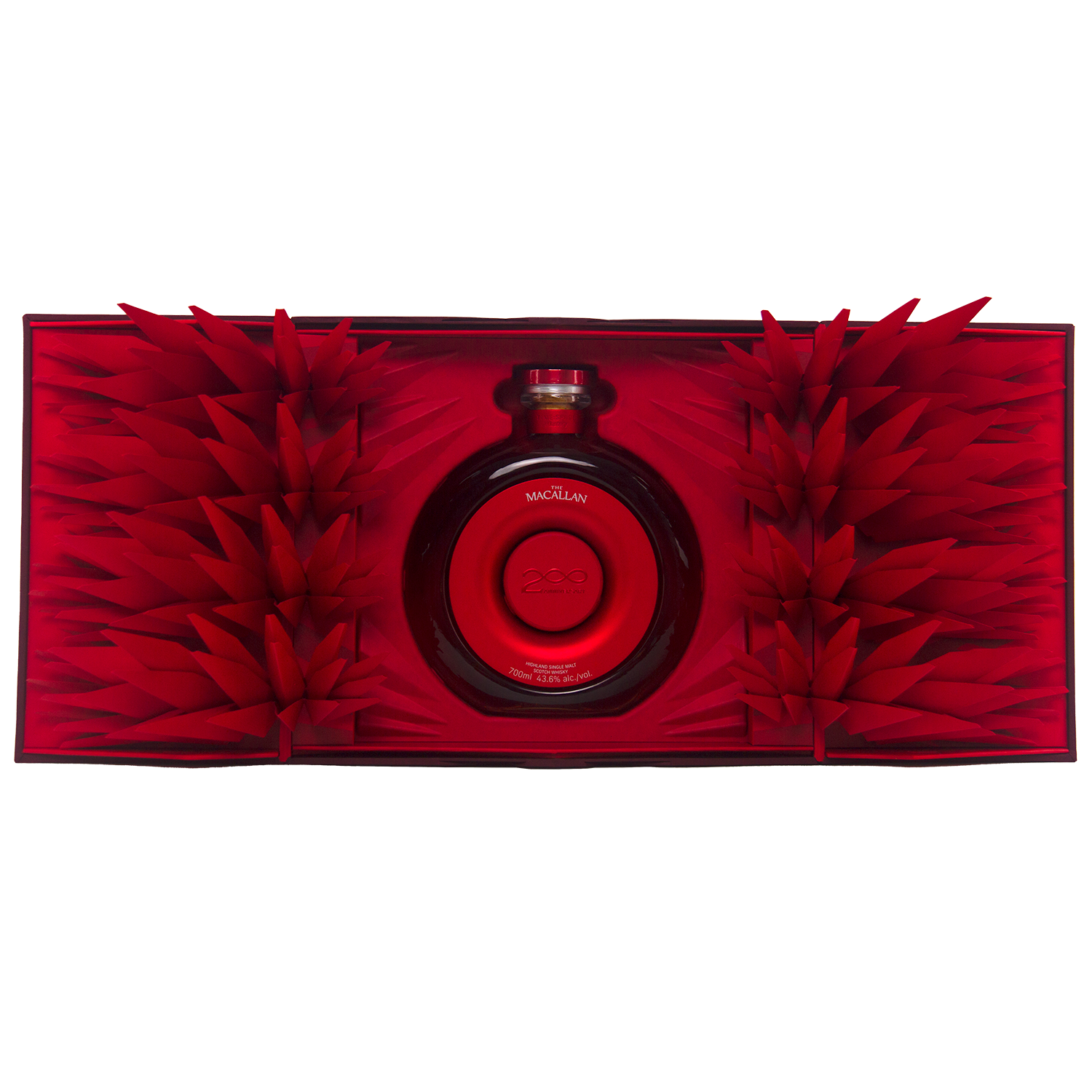 A round red bottle of The Macallan Time Space Mastery Single Malt Scotch Whisky sits at the center of an open, ornate red box adorned with geometric paper spikes, creating a striking and luxurious collectible display.