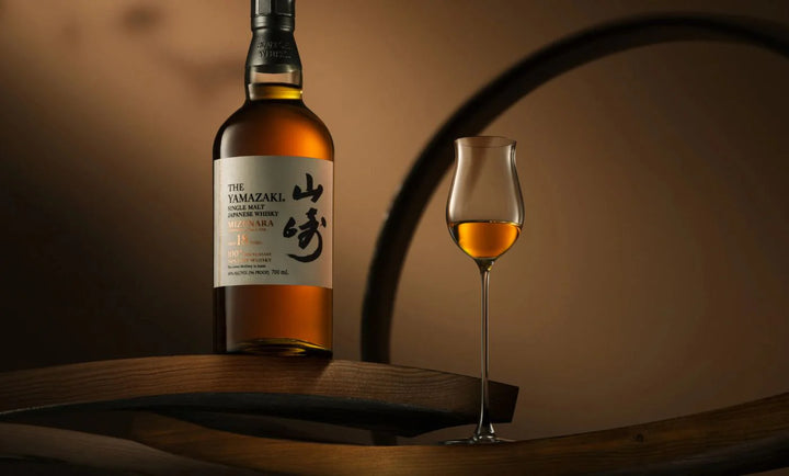 Bottle of Yamazaki whisky with a glass on a wooden barrel