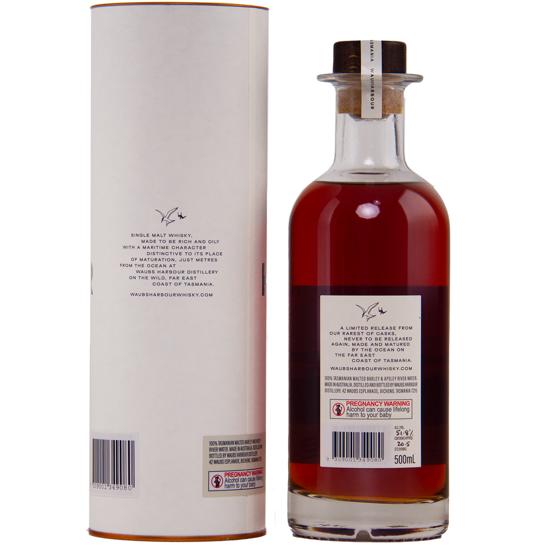 A 500ml bottle of Waubs Harbour Yeast Cask Single Malt Australian Whisky, rich amber in color with a clear glass stopper, stands beside its cylindrical packaging. Both feature labels and a signature logo. Limited-edition Australian whisky.