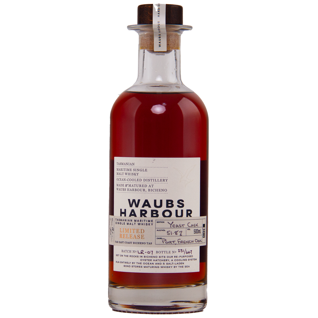 A clear glass bottle of Waubs Harbour Yeast Cask Single Malt Australian Whisky with a cork stopper. This deep amber, limited-edition Australian whisky is matured in a yeast cask, as described on the label.