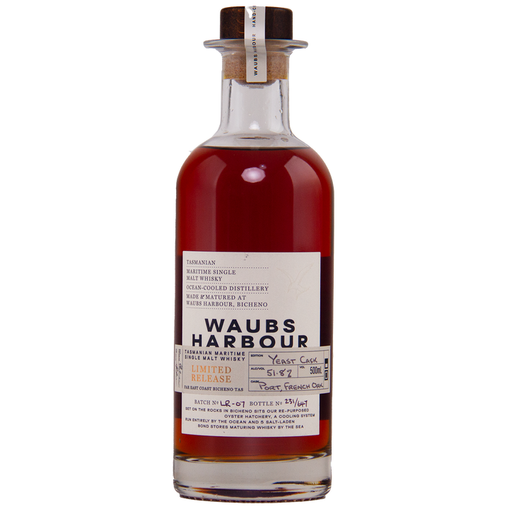 A clear glass bottle of Waubs Harbour Yeast Cask Single Malt Australian Whisky with a cork stopper. This deep amber, limited-edition Australian whisky is matured in a yeast cask, as described on the label.