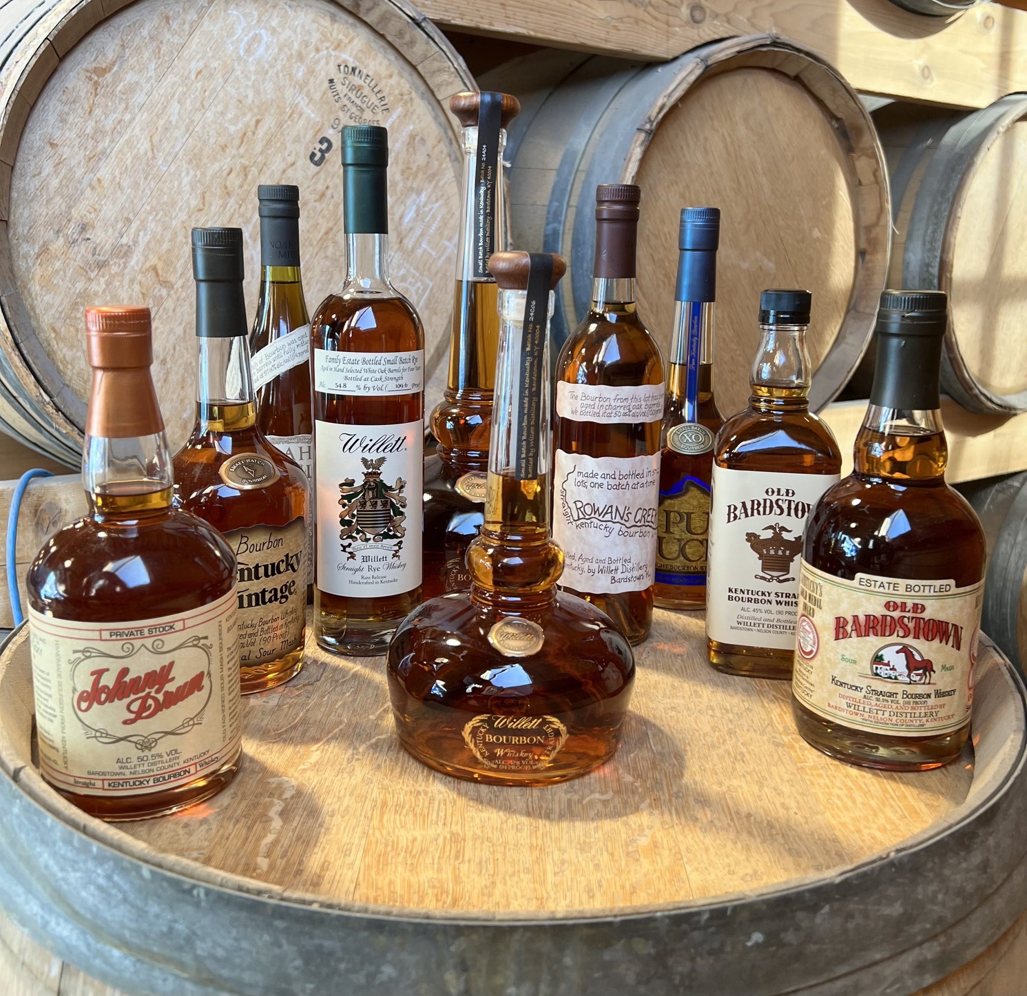 Assorted whiskey bottles on a wooden barrel with barrels in the background