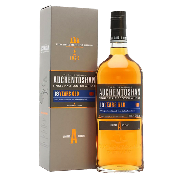 A bottle of Auchentoshan 18 Year Old Single Malt Scotch Whisky is placed beside its grey and orange box, with labels highlighting triple distillation, limited release, and a 700 ml size.