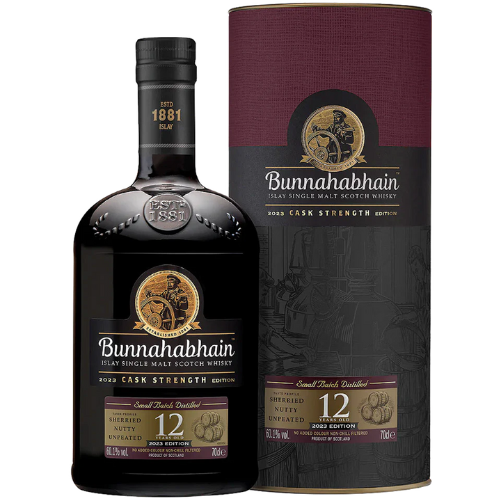 A bottle of Bunnahabhain 12 Year Old Cask Strength Single Malt Scotch Whisky stands before its cylindrical box, both featuring gold and maroon labels with the distillery’s logo and whisky details.