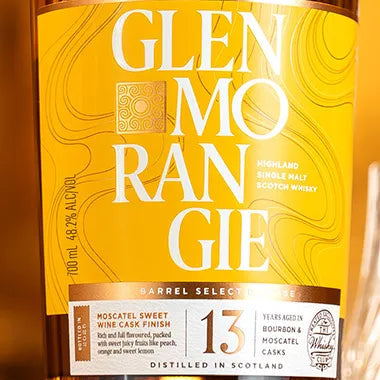 Close-up of a Glen Morangie 13 Year Old whisky bottle, showing the yellow and white label with the brand name in large white letters.
