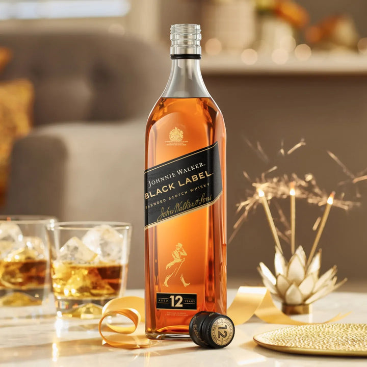Johnnie Walker Black Label whisky bottle with glasses and decorative elements on a table.