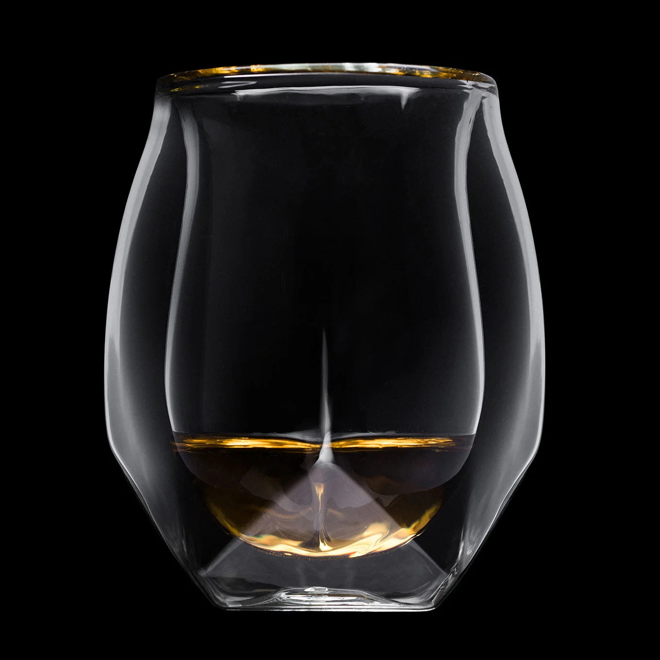 A clear double-walled glass tumbler with a gold rim, shown against a solid black background. The bottom half of the inner glass is filled with amber-colored liquid, creating a reflective gold base.