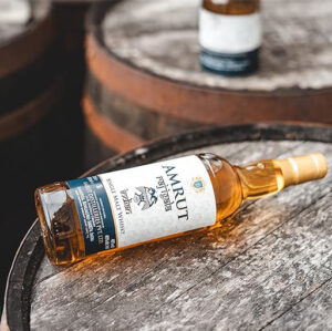 Amrut Raj Igala whisky bottle and canister packaging available at Whisky Estate, featuring a sleek design that reflects its Indian heritage. The clear glass bottle reveals the golden amber whisky, while the stylish canister enhances the presentation, highlighting its balanced flavor profile with notes of honey, vanilla, and tropical fruits, offering a smooth and elegant tasting experience. - Whisky Estate