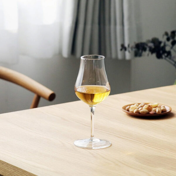 A luxurious Luigi Bormioli whisky glass on a modern timber table accompanied by roasted mixed nuts - Whisky Estate